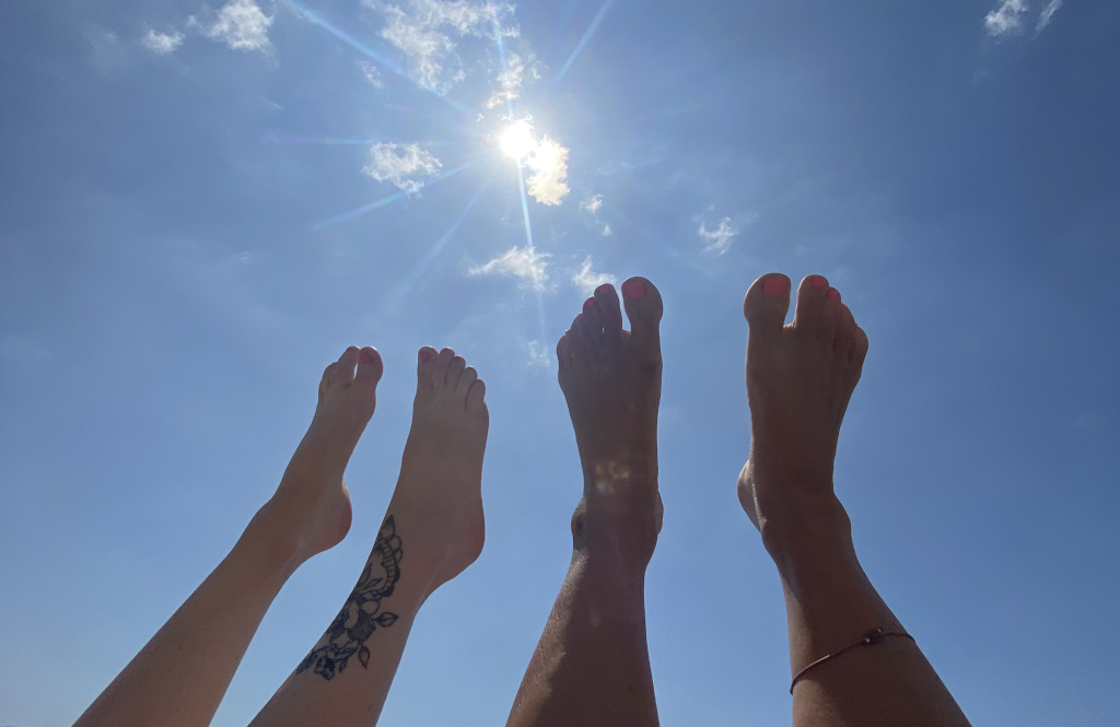 Two pairs of bare feet raised upwards in the sunshine